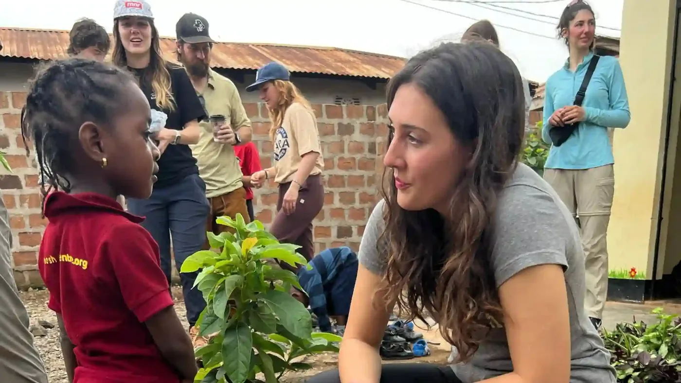 Visiting travellers sitting with a young child holding a tree seedling ready to plant.